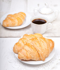 Two croissants with coffee on the white table