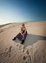 Fototapeta na wymiar woman in dress sitting on sand dune