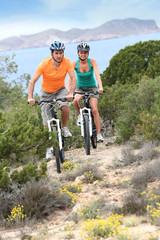Couple riding bikes on island trail
