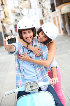 Couple taking picture of themselves on scooter