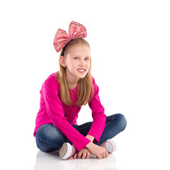 Little girl with hair bow sitting with legs crossed.