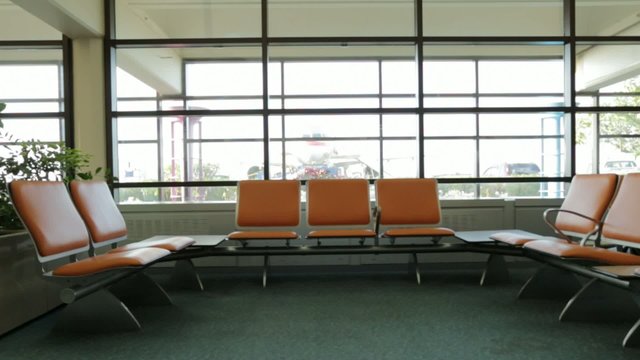 Seats at airport with airplane and cars in back