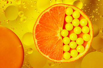 Orange slice with vitamin pills on abstract background