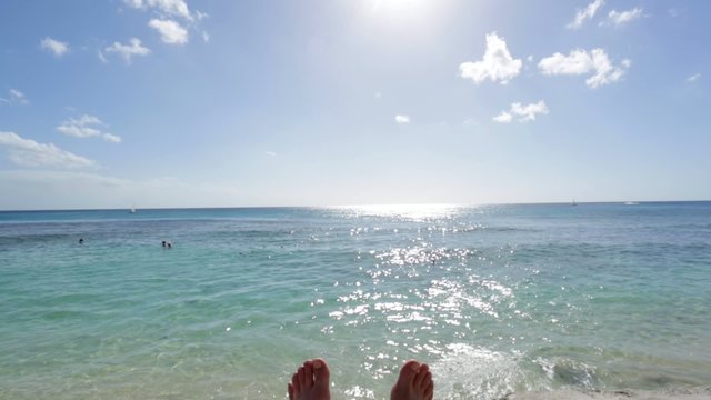 Feet relaxing by the ocean on a sunny day with clear blue sky