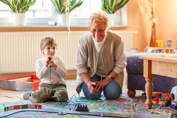 Grandmother and little grandson playing with racing cars