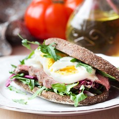 Sandwich with grilled beef steak, eggs, arugula, rye bread
