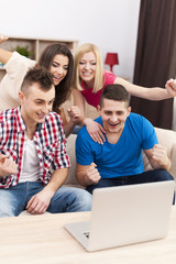 Excited friends watching soccer match on laptop