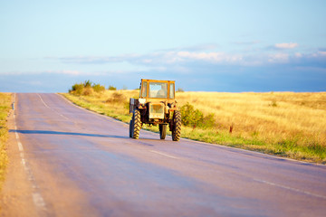 farmer drives tractor on country road