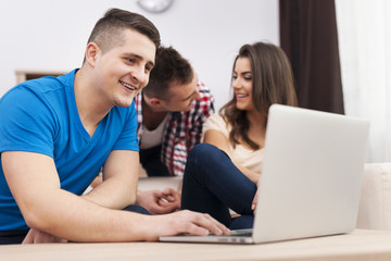 Smiling man using laptop with friends at home