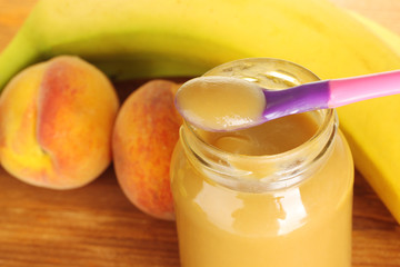Jar with fruit baby food, spoon and fruits