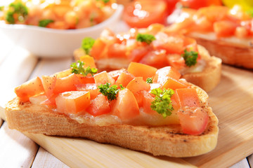 Delicious bruschetta with tomatoes on cutting board close-up