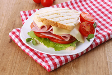 Tasty sandwich with ham on wooden table