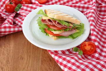 Tasty sandwich with ham on wooden table
