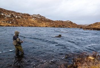 Man fishing for trout and salmon in a  Scottish loch