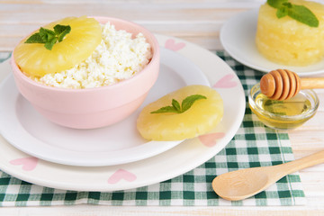 Bowl of tasty cottage cheese with pineapple on wooden table