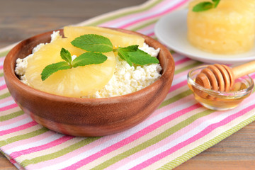Bowl of tasty cottage cheese with pineapple on wooden table