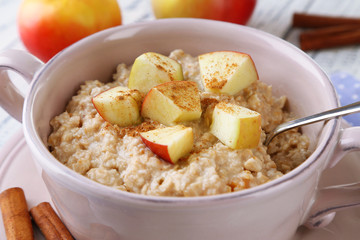 Tasty oatmeal with apples and cinnamon on wooden table