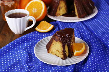 Piece of delicious cake  with oranges on table close-up
