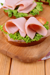 Delicious sandwiches with lettuce and ham on table close-up