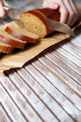 Female hands cutting bread on wooden board, close-up