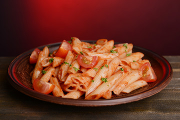 Pasta with tomato sauce on plate on table on red background