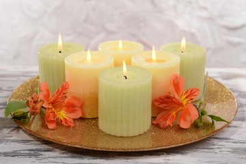 Beautiful candles with flowers on table on grey background
