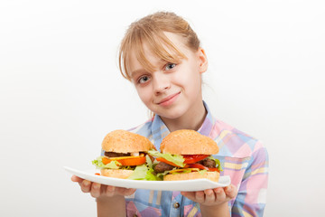 Little smiling blond girl with homemade hamburgers on white plat