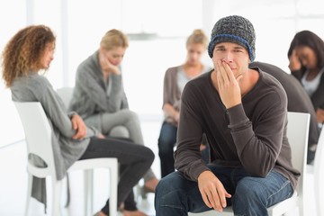 Upset man in rehab group looking at camera