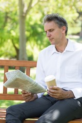Fototapeta premium Businessman reading newspaper in park