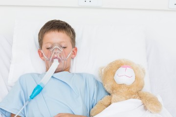 Boy wearing oxygen mask sleeping beside stuffed toy