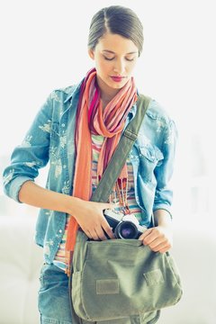 Young pretty woman taking camera from her bag