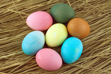 Colorful Easter eggs on straw background closeup