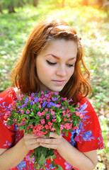 Naklejka premium Beautiful young woman with the bouquet of spring flowers