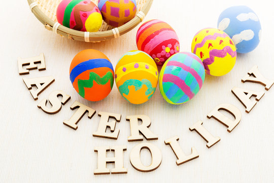 Colourful easter egg in basket with wooden text