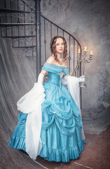 Beautiful woman in blue medieval dress with candelabrum