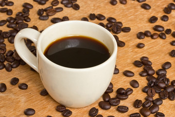Cup of black coffee and coffee beans on wooden background.