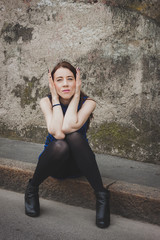 Pretty girl sitting on sidewalk