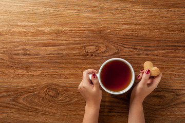 woman holding hot cup of tea with cookies