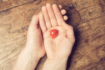 Hands holding heart shaped tomato