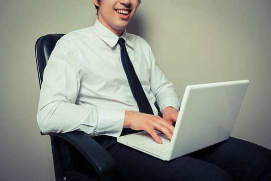 Businessman in office chair working on laptop