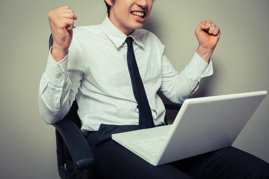 Excited young businessman with laptop