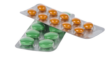 Green and orange pills in blisters on white background