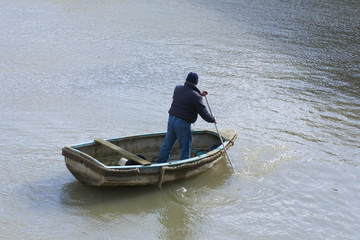 Single fishing man in small rowing boat