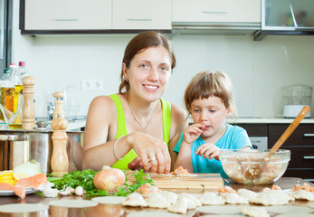  woman with child cooking fish pelmeni (pelmeni), today together