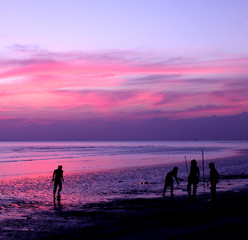 Silhouettes of people playing football on the beach when the sun