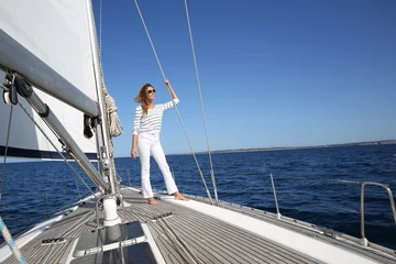 Papier Peint photo Naviguer Attractive woman standing on sailboat deck