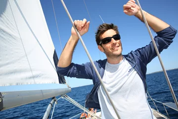Afwasbaar Fotobehang Zeilen Schipper staat op zeilboot tijdens het zeilen