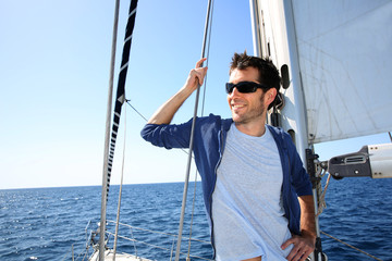 Skipper debout sur un voilier en naviguant