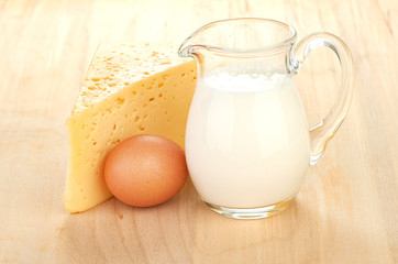 Big piece of cheese, glass jug with milk