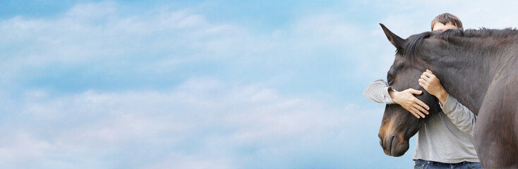 Man hugging his black horse's head against  sky, banner